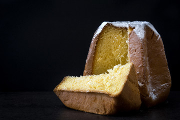 Pandoro Christmas cake with sugar on black background.Copyspace