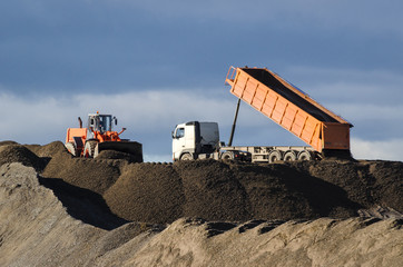 CONSTRUCTION SITE - Construction machine and track on the heap of stored building material
