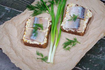 Herring, green onions, butter, French mustard and a slice of rye bread on an old wooden table.
