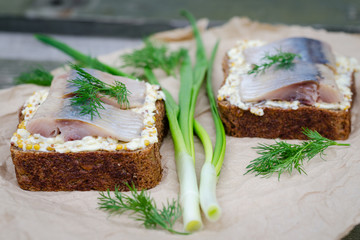 Herring, green onions, butter, French mustard and a slice of rye bread on an old wooden table.