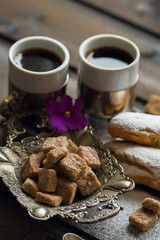 Cake eclair with coffee and cane sugar on a wooden background