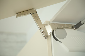 Detail of hinge on door of a kitchen cupboard