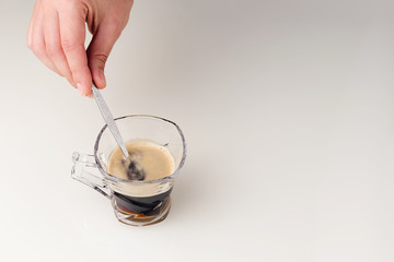 Espresso coffee in glass cup with vintage spoon on white glass table