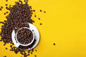 Wall murals Coffee bar Coffee cup with beans on yellow background.