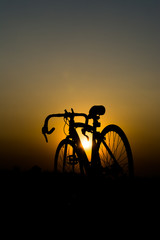 Naklejka premium a silhouette of a bicycle with the sun setting behind it.