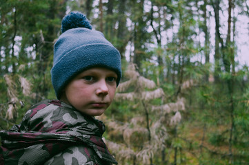 The boy, walking in the woods heard something and looked around