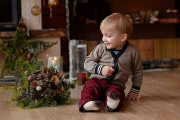 Little child near the fireplace with flowers. Merry Christmas. Happy New Year.