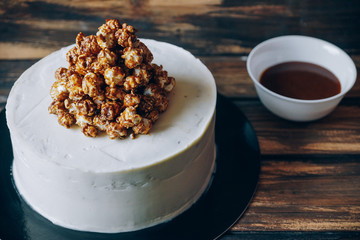 Cheesecake with caramel popcorn and chocolate souse on the wooden background top view. Artwork.