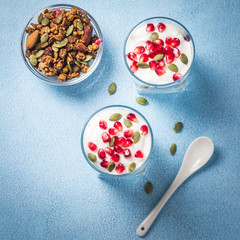 Breakfast parfait with greek yougurt, pumpkin seeds and berries on light blue background. Top view, copy space.