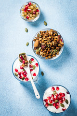 Fruit and yogurt granola parfait on light blue background. Top view, copy space.