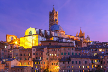Beautiful view of Dome and campanile of Siena Cathedral, Duomo di Siena, and Old Town of medieval city of Siena during evening blue hour, Tuscany, Italy