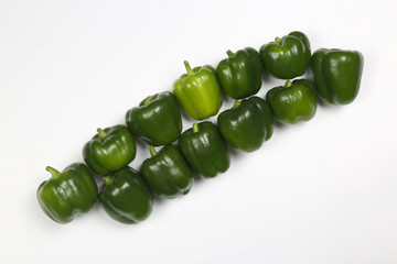 laid out in a row of green peppers on white background.