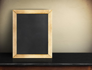 Blank blackboard on black marble table at yellow concrete wall,Template mock up for adding your design and leave space beside frame for adding more text.