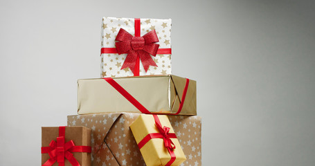 Christmas present in boxes with beautiful paper and ribbons piled up gradually isolated on white