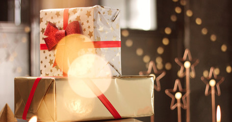 Beautifully wrapped Christmas presents on the background of stylish decorations and lights in warm golden and red tones