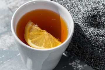 Close up white cup of lemon tea wrapped in blanket