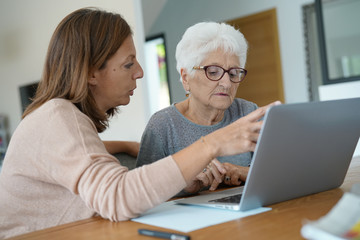 Elderly woman using laptop with help of homecarer