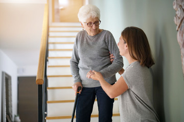 Homecare helping elderly woman going down the stairs - 179703842