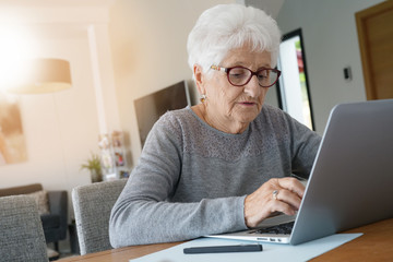 Old woman at home using laptop computer