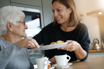 Homecarer serving tea to elderly woman