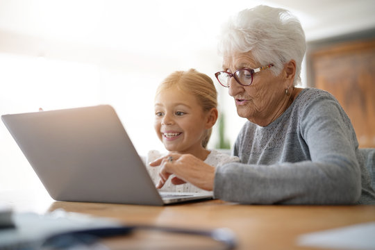 Little girl with grandmother using laptop computer