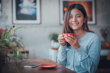 Asian business girl working and drinking coffee in cafe with laptop
