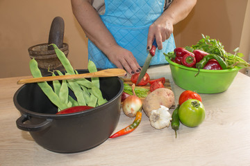 Woman's hands cooking healthy meal in the kitchen, behind fresh vegetables. Cropped image of young girl cutting vegetables for Food