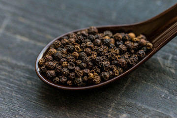 Close up black peppercorn in spoon dark background