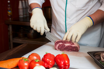 Chef cutting meat on steaks with knife