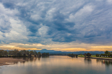 Landscape of river with trees and overcast skies at dusk