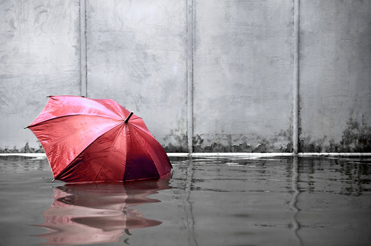 Red umbrella floating concept. Flooded on street. .Waiting for help me after the rain. Black and white colors. Close up.