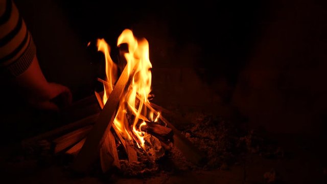 Fire in a fireplace. 4k, slow motion. woman puts firewood in the fireplace