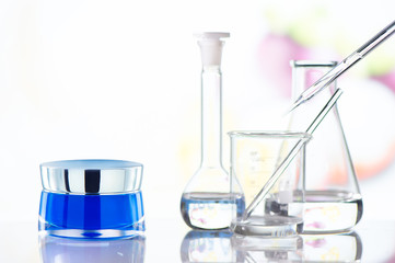 Cream jar with science glass on glass table. Front view.