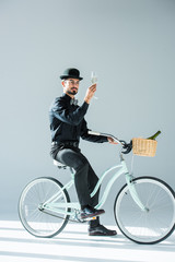 man on retro bicycle with glass of champagne