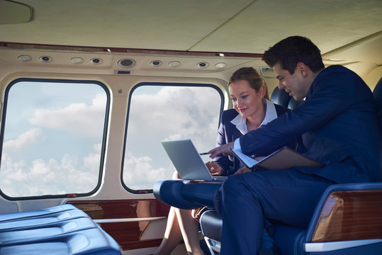 Businessman And Businesswoman Working On Laptop In Helicopter Cabin