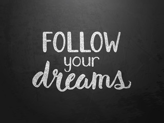 Fototapeta na wymiar FOLLOW YOUR DREAMS motivational quote written on blackboard