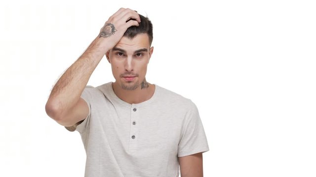 horizontal portrait of tense brunette man with tattoo on body clutching his head  being nervous stressed thinking about solution of problem over white background closeup. Concept of emotions