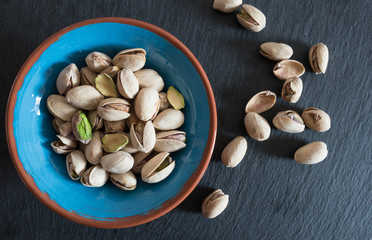roasted pistachios in a bowl on slate surface
