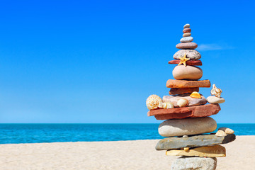 Fototapeta na wymiar seashells and rock Zen on the background of sea and blue sky