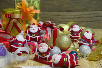 Stacks of Christmas presents with ornaments and santa laid on a wooden  table and wood background. Selective focus.