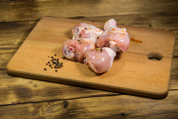 Raw chicken legs with spices on wooden table