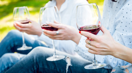 Young beautiful girls with glass of red wine in the park
