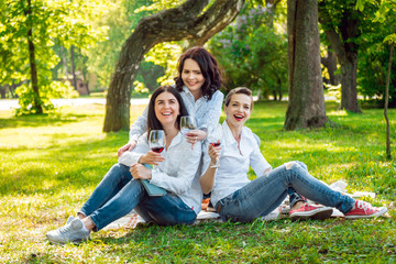 Naklejka na ściany i meble Young beautiful girls with glass of red wine in the park