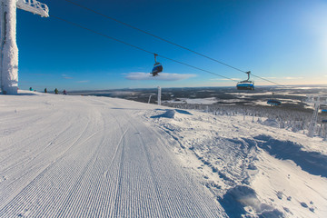 Fototapeta na wymiar Beautiful cold mountain view of ski resort, sunny winter day with slope, piste and ski lift