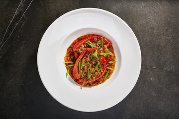 Baked peppers stuffed with vegetables and rice sprinkled with fresh herbs on black background