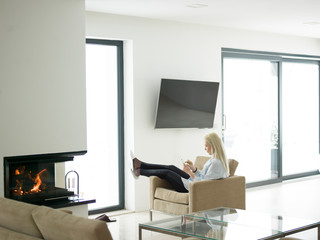 young woman using tablet computer in front of fireplace