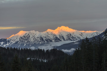 Fototapeta na wymiar Aufnahme der Kanzelwand im Abendlicht mit von der Abendsonne angestrahltem Gipfel tor glühend und Nebelschleiern im Tal aufgenommen im Winter 2013