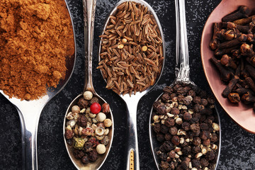Various spices and spoons on dark table.