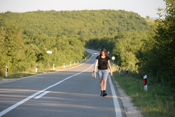 Woman Walking on the road in mountains at sunset. Forty Years old woman on the road