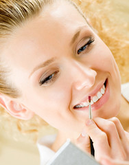 Cheerful smiling woman applying lipstick